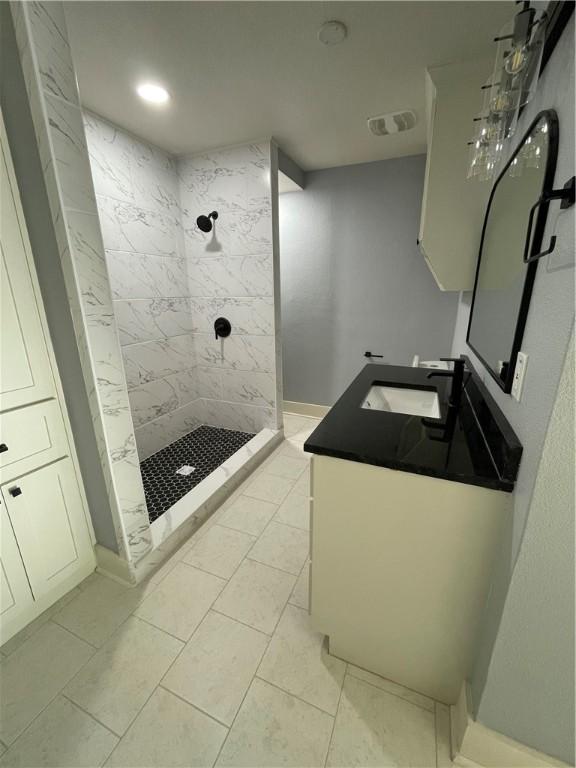 bathroom with tiled shower, vanity, and tile patterned flooring