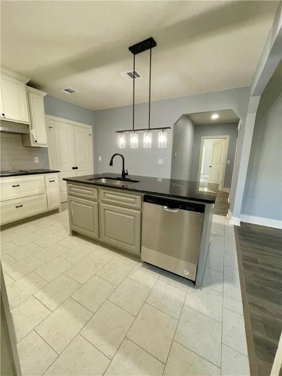 kitchen featuring stainless steel dishwasher, sink, decorative light fixtures, white cabinets, and an island with sink