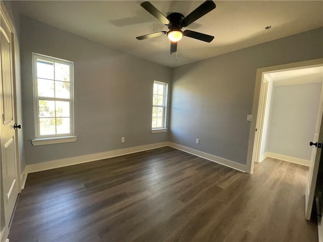 unfurnished room featuring ceiling fan, a healthy amount of sunlight, and dark hardwood / wood-style floors