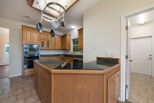 kitchen with kitchen peninsula, light tile patterned floors, sink, and black appliances