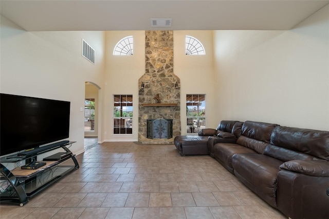 tiled living room with plenty of natural light, a towering ceiling, and a fireplace