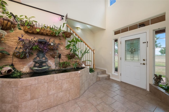 foyer entrance with light tile patterned flooring and a towering ceiling