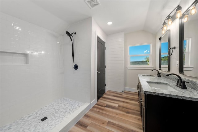 bathroom with tiled shower, wood-type flooring, vanity, and vaulted ceiling