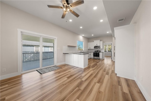 kitchen with white cabinets, light hardwood / wood-style flooring, ceiling fan, appliances with stainless steel finishes, and kitchen peninsula