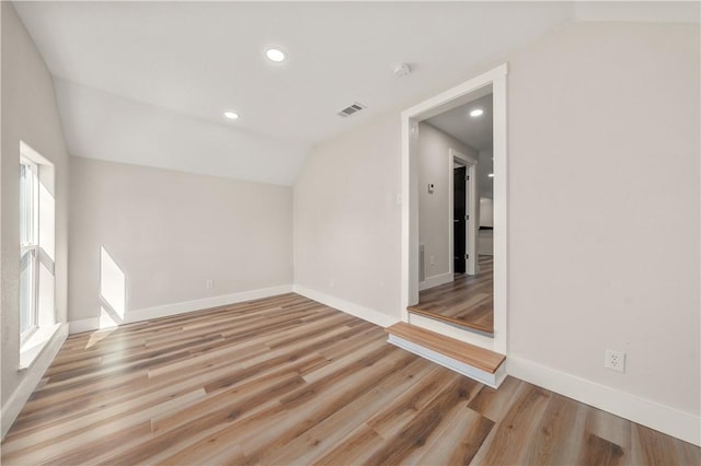 additional living space with light hardwood / wood-style floors and vaulted ceiling