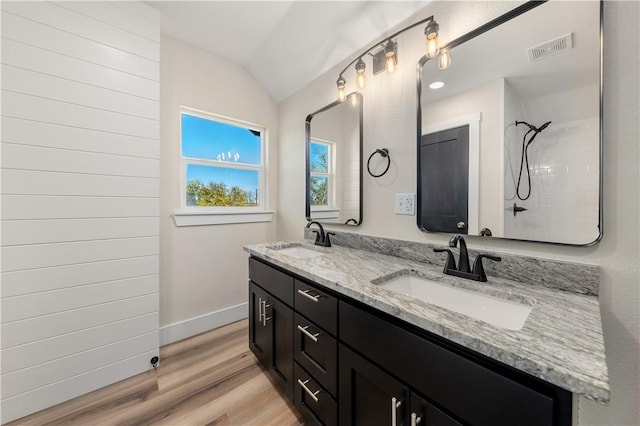 bathroom featuring tiled shower, hardwood / wood-style floors, vanity, and vaulted ceiling