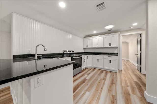 kitchen with kitchen peninsula, stainless steel electric range oven, sink, and white cabinets