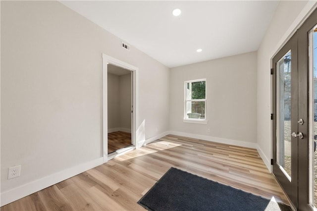 empty room featuring french doors and light wood-type flooring