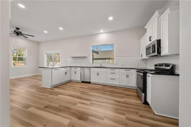 kitchen with ceiling fan, white cabinets, stainless steel appliances, and light hardwood / wood-style floors