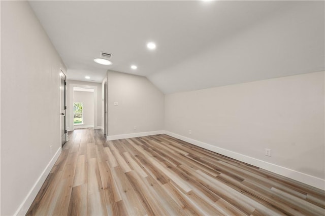 additional living space with light hardwood / wood-style flooring and vaulted ceiling