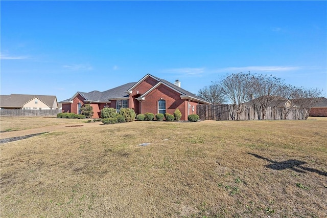 view of front of house featuring brick siding, fence, a chimney, and a front lawn