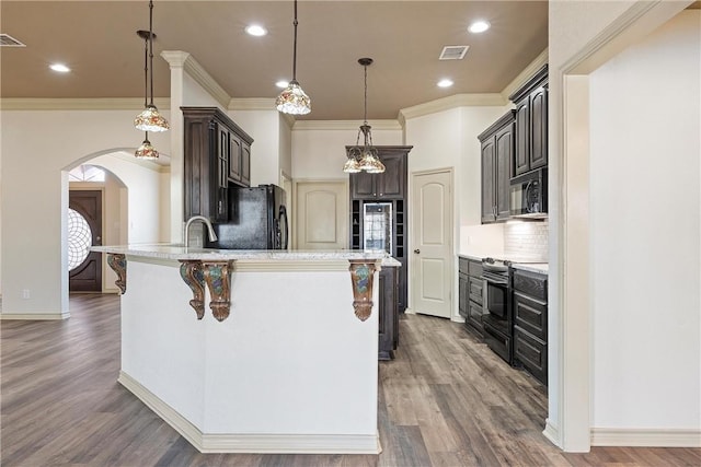 kitchen with arched walkways, a peninsula, wood finished floors, visible vents, and black appliances