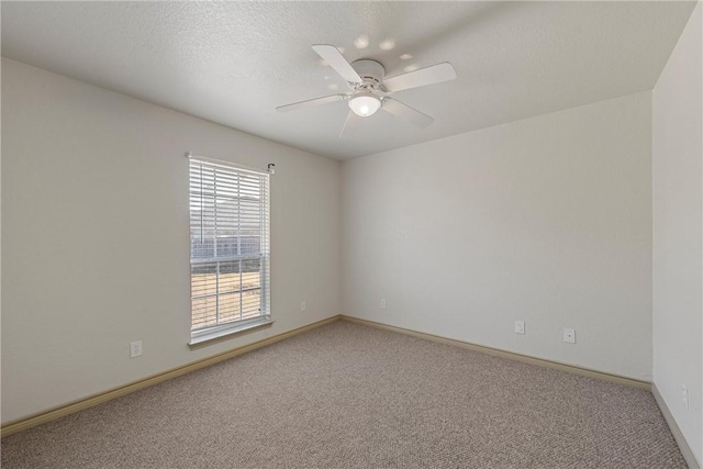 empty room with light carpet, a textured ceiling, baseboards, and a ceiling fan