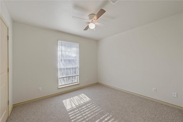 carpeted spare room with ceiling fan and baseboards