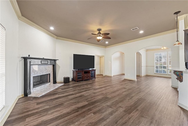 living room featuring visible vents, dark wood finished floors, arched walkways, a ceiling fan, and a fireplace