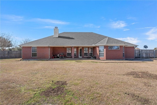 back of house featuring brick siding, a yard, and fence