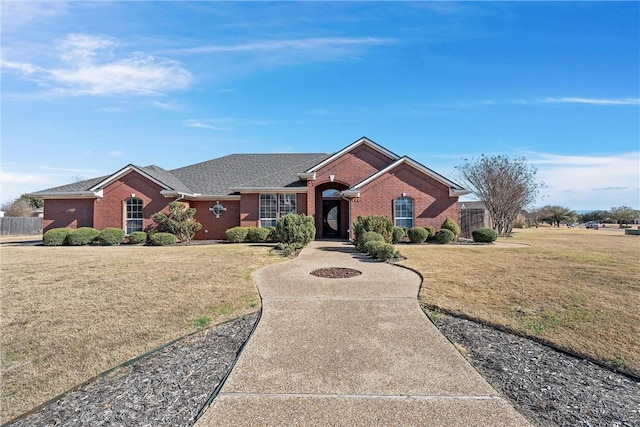 ranch-style home featuring brick siding, a front lawn, and fence