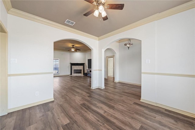 spare room featuring a fireplace, visible vents, ornamental molding, ceiling fan, and wood finished floors