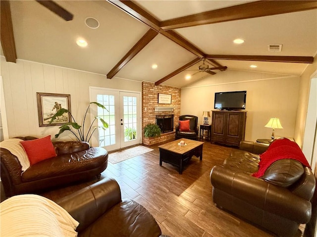 living room featuring dark hardwood / wood-style floors, a fireplace, vaulted ceiling with beams, ceiling fan, and french doors