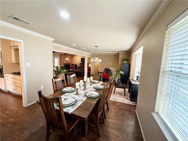 dining room featuring crown molding, a fireplace, and an inviting chandelier