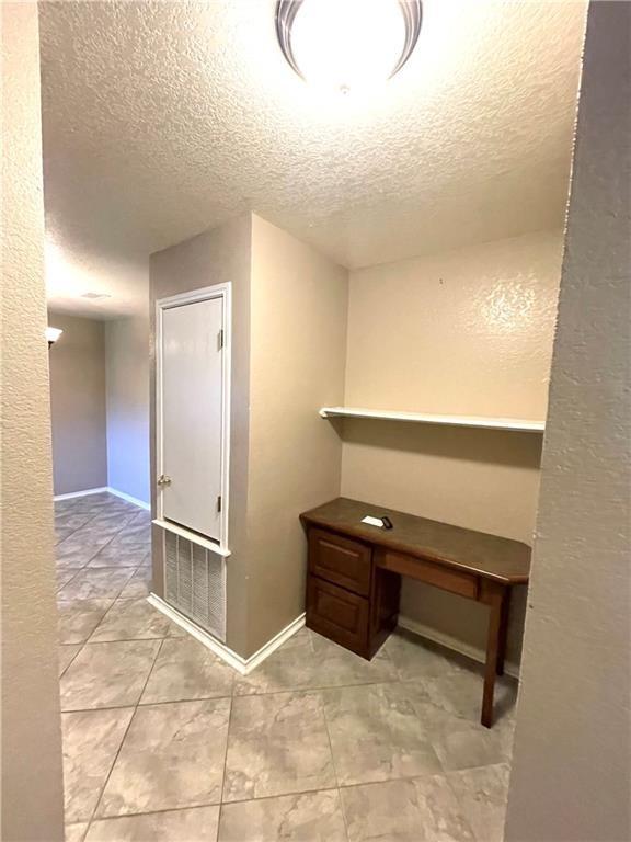 interior space with light tile patterned floors and a textured ceiling