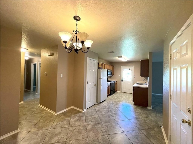 kitchen with light tile patterned floors, a textured ceiling, white fridge, and a notable chandelier