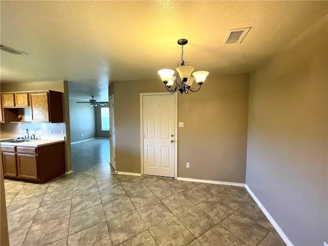 unfurnished dining area with ceiling fan with notable chandelier, sink, and a textured ceiling