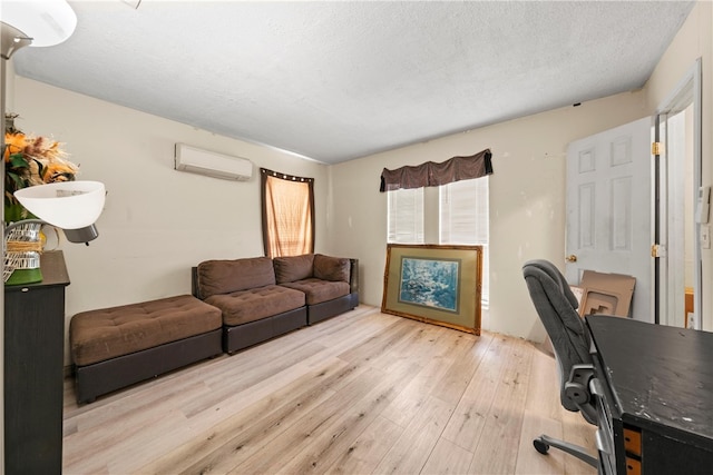 office featuring a textured ceiling, light wood-type flooring, and a wall unit AC