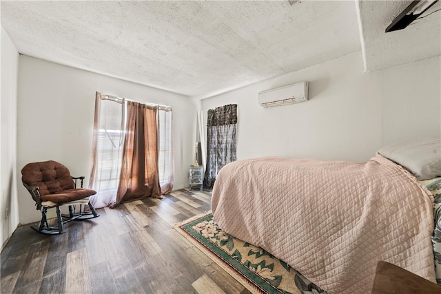 bedroom featuring a wall mounted AC, wood-type flooring, and a textured ceiling