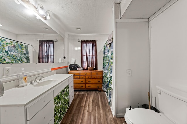 bathroom with hardwood / wood-style flooring, vanity, toilet, and a textured ceiling