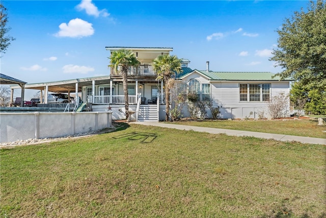 view of front of property featuring covered porch, metal roof, a balcony, and a front lawn