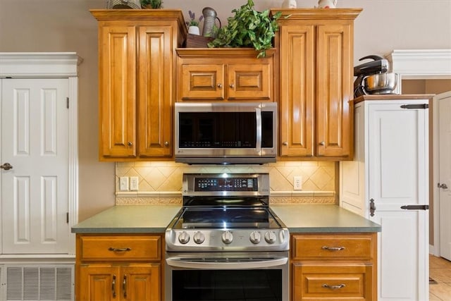 kitchen with backsplash, light tile patterned floors, and appliances with stainless steel finishes