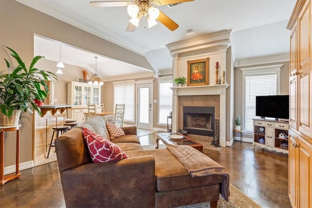 living room with ceiling fan with notable chandelier, ornamental molding, dark wood-type flooring, and a tiled fireplace