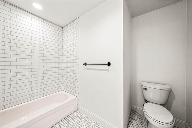 bathroom featuring tile patterned flooring, tiled shower / bath combo, and toilet