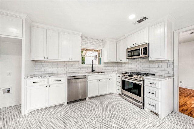 kitchen with light stone counters, sink, white cabinets, and appliances with stainless steel finishes