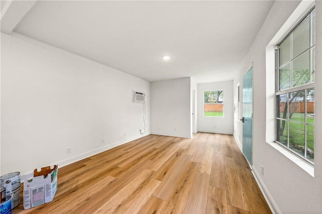 spare room featuring a wall mounted AC and light wood-type flooring