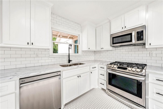 kitchen with appliances with stainless steel finishes, light stone counters, white cabinetry, and sink