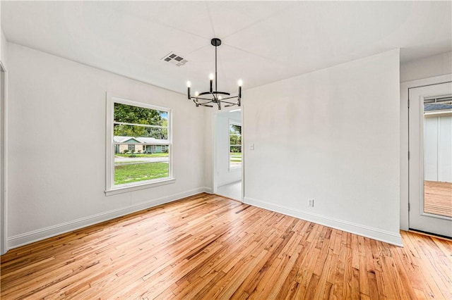 unfurnished room featuring light wood-type flooring and an inviting chandelier