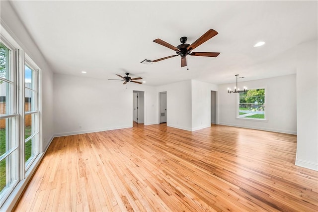 unfurnished living room with ceiling fan with notable chandelier and light hardwood / wood-style flooring