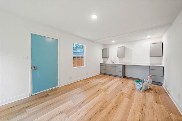 interior space featuring gray cabinets, sink, built in desk, and light hardwood / wood-style floors