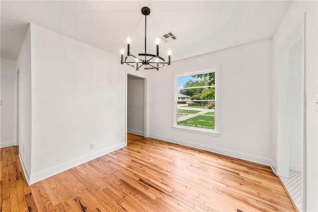 unfurnished dining area featuring light wood-type flooring and a chandelier