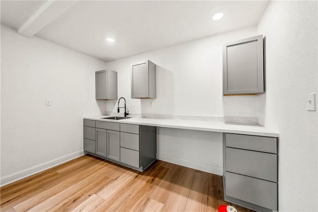 kitchen with gray cabinets, sink, and light wood-type flooring