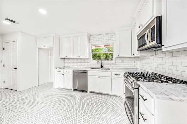 kitchen with light stone counters, white cabinetry, sink, and appliances with stainless steel finishes