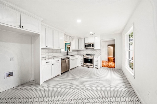 kitchen featuring decorative backsplash, a healthy amount of sunlight, white cabinets, and stainless steel appliances