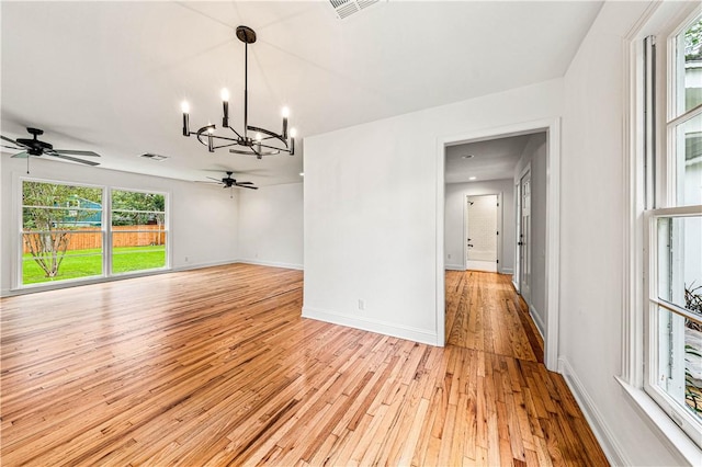 unfurnished room with ceiling fan with notable chandelier and light wood-type flooring