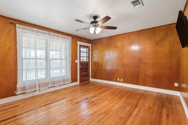 unfurnished room with wooden walls, ceiling fan, and hardwood / wood-style flooring