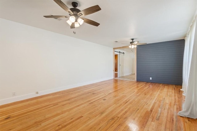 unfurnished room with a barn door and light hardwood / wood-style floors