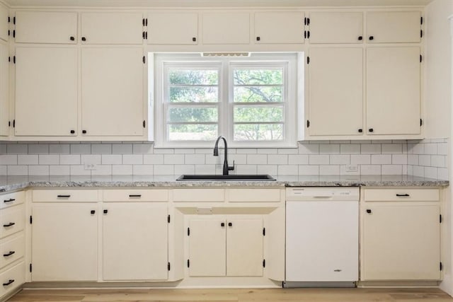 kitchen with dishwasher, light wood-type flooring, light stone countertops, and sink