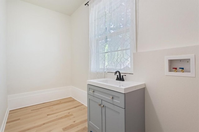 clothes washing area with hookup for a washing machine, light wood-type flooring, and sink