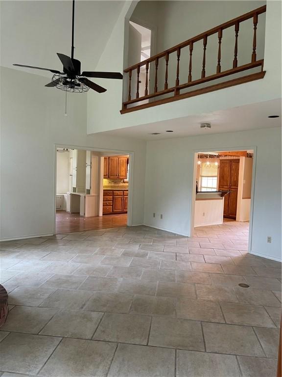 unfurnished living room with a towering ceiling and ceiling fan